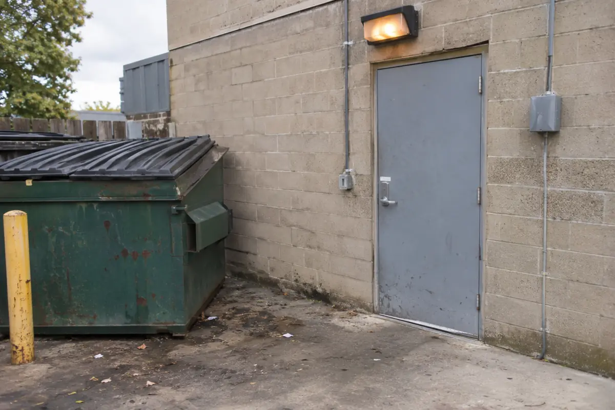 Restaurant back door beside a dumpster pad, a frequent focus of commercial rodent control Greensboro programs